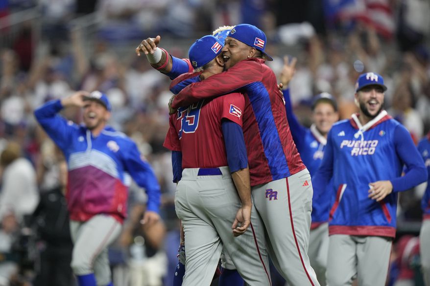 Puerto Rico pitcher Edwin Diaz, foreground is mobbed by teammates after Puerto Rico beat the Dominican Republic 5-2 during a World Baseball Classic game, Wednesday, March 15, 2023, in Miami. Diaz appeared to injure himself during the postgame celebration. (AP Photo/Wilfredo Lee)