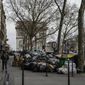 People walk past uncollected garbages in Paris, Friday March 17, 2023, as sanitation workers are on strike. Protests against French President Emmanuel Macron&#x27;s decision to force a bill raising the retirement age from 62 to 64 through parliament without a vote disrupted traffic, garbage collection and university campuses in Paris as opponents of the change maintained their resolve to get the government to back down. Arc de Triomphe in the background. (AP Photo/Lewis Joly)