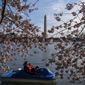 Visitors paddle past Yoshino cherry blossoms and the Washington Monument near the Tidal Basin on Saturday, March 18, 2023, in Washington. (AP Photo/Nathan Howard)
