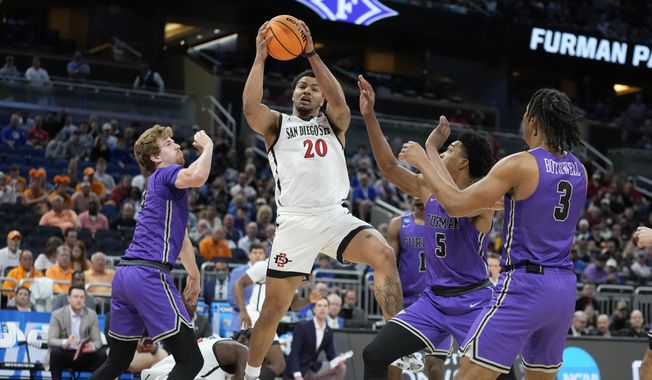 San Diego State guard Matt Bradley (20) grabs a rebound away from Furman forward Garrett Hien (13), guard Mike Bothwell (3) and guard Marcus Foster (5) during the first half of a second-round college basketball game in the NCAA Tournament Saturday, March 18, 2023, in Orlando, Fla. (AP Photo/Chris O&#x27;Meara)