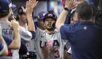 United States&#x27; Mookie Betts (3) is congratulated by teammates after he scored on a throwing error by Venezuela center fielder Ronald Acuna Jr., during the first inning of a World Baseball Classic game, Saturday, March 18, 2023, in Miami. (AP Photo/Wilfredo Lee)