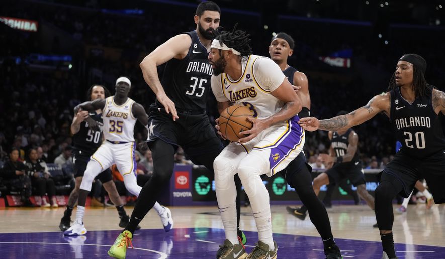 Los Angeles Lakers forward Anthony Davis (3) is defended by Orlando Magic&#x27;s Goga Bitadze, left, and Markelle Fultz (20) during the first half of an NBA basketball game Sunday, March 19, 2023, in Los Angeles. (AP Photo/Marcio Jose Sanchez)