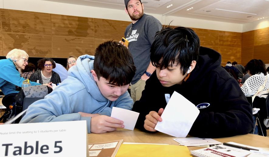 Meadowdale High School ninth grade students Juanangel Avila, right, and Legacy Marshall, left, work together to solve an exercise at MisinfoDay, an event hosted by the University of Washington to help high school students identify and avoid misinformation, Tuesday, March 14, 2023, in Seattle. Educators around the country are pushing for greater digital media literacy education. (AP Photo/Manuel Valdes)