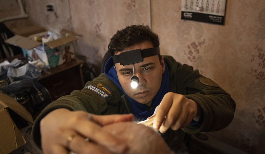 A medical volunteer of FRIDA Ukraine examines a patient's nose during providing specialist medical care for civilians in Khrestysche village, Donetsk region, Ukraine, Sunday, March 19, 2023. The Ukrainian-Israeli medical aid organization FRIDA Ukraine, staffed by volunteer doctors, has been providing specialist medical care through mobile clinics in villages and towns near the front lines and in recently retaken areas. (AP Photo/Evgeniy Maloletka)