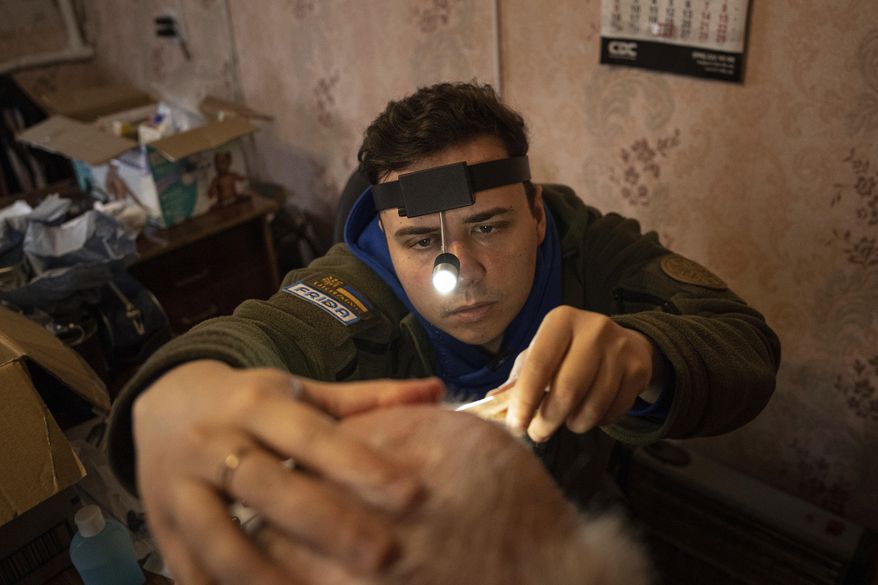A medical volunteer of FRIDA Ukraine examines a patient's nose during providing specialist medical care for civilians in Khrestysche village, Donetsk region, Ukraine, Sunday, March 19, 2023. The Ukrainian-Israeli medical aid organization FRIDA Ukraine, staffed by volunteer doctors, has been providing specialist medical care through mobile clinics in villages and towns near the front lines and in recently retaken areas. (AP Photo/Evgeniy Maloletka)