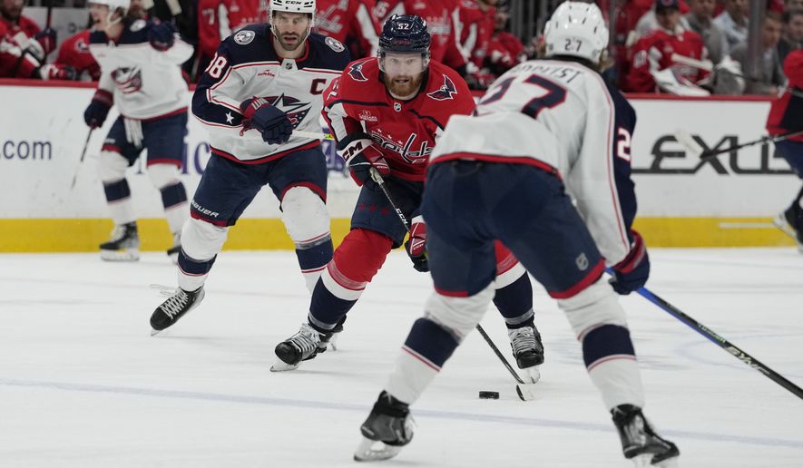 Washington Capitals defenseman Matt Irwin (52) skates with the puck against Columbus Blue Jackets center Boone Jenner (38) and Columbus Blue Jackets defenseman Adam Boqvist (27) during the first period of an NHL hockey game Tuesday, March 21, 2023, in Washington. The Blue Jackets won 7-6 in overtime. (AP Photo/Carolyn Kaster)