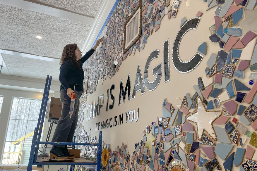 Artist Mia Schon finishes a mural in one of the activity rooms of the Hole In the Wall Gang Camp, March 2, 2023, in Ashford, Conn. Two years after a fire devastated Paul Newman's camp for seriously ill children, the rebuilt camp center is opening. The new $4.5 million center has twice the space with more accessibility and new amenities such as a quiet sensory room, a dedicated room with a fireplace for parents and caregivers, and an emergency storm shelter and cistern, in case of another fire.(AP Photo/Pat Eaton Robb)