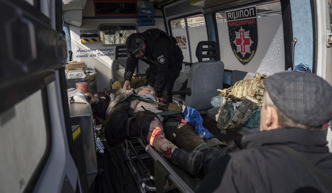 A Ukrainian police officer of the White Angels unit, loads an injured woman on a stretcher into a van after shelling by Russian forces, during her evacuation to a hospital in Kostiantynivka, Ukraine, Friday, March 10, 2023. For months, authorities have been urging civilians in areas near the fighting in eastern Ukraine to evacuate to safer parts of the country. But while many have heeded the call, others -– including families with children -– have steadfastly refused. (AP Photo/Evgeniy Maloletka)