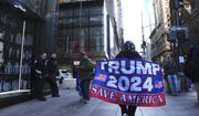 A woman walks on Fifth Avenue carrying a flag showing support for former President Donald Trump, on Tuesday, March 21, 2023, in New York. (AP Photo/Bryan Woolston)