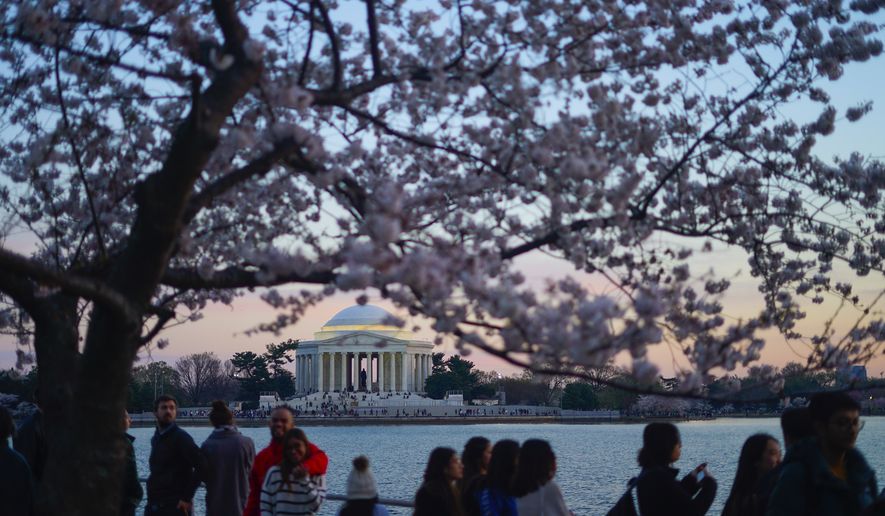 People walk along the Tidal Basin during sunset as cherry blossoms enter their peak bloom this week, Wednesday, March 22, 2023, in Washington. (AP Photo/Pablo Martinez Monsivais) ** FILE **