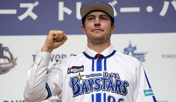 Trevor Bauer with his new uniform and cap of Yokohama DeNA BayStars poses for photographers during a photo session of the news conference Friday, March 24, 2023, in Yokohama, near Tokyo. (AP Photo/Eugene Hoshiko)