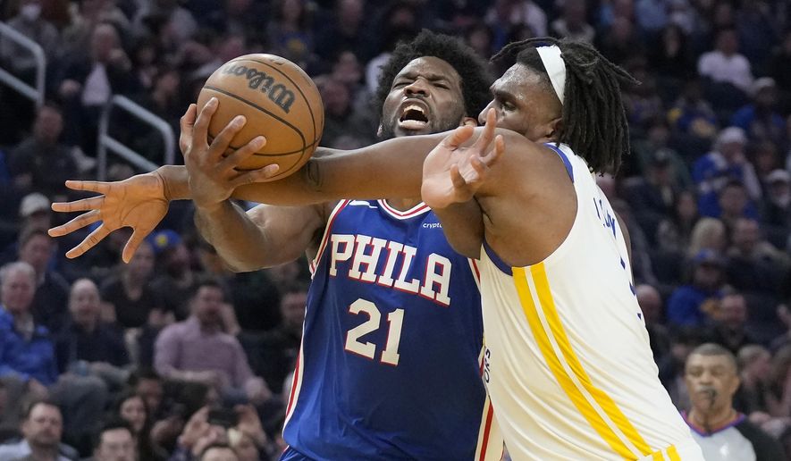 Philadelphia 76ers center Joel Embiid (21) is fouled by Golden State Warriors forward Kevon Looney while driving to the basket during the first half of an NBA basketball game in San Francisco, Friday, March 24, 2023. (AP Photo/Jeff Chiu)