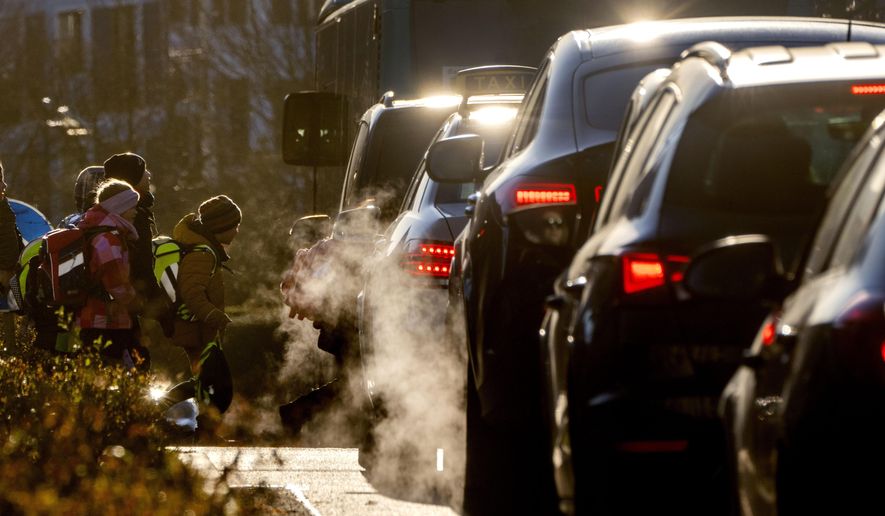 FILE - Cars give off exhaust fumes as children head to school in Frankfurt, Germany, on Monday, Feb. 27, 2023. Germany and the European Union said Saturday, March 25, 2023 that they reached an agreement in their dispute over the future of cars with combustion engines allowing the registration of new vehicles with combustion engines even after 2035 if they use climate-neutral fuel only. (AP Photo/Michael Probst, File)