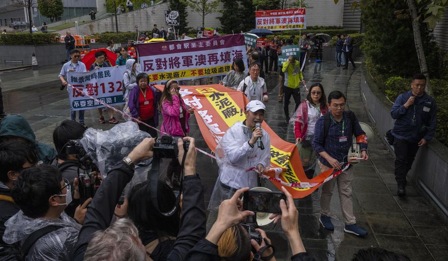 Protesters walk within a cordon line wearing number tags during a rally in Hong Kong, Sunday, March 26, 2023. Dozens of people on Sunday joined Hong Kong&#x27;s first authorized demonstration against the government since the lifting of major COVID-19 restrictions under unprecedentedly strict rules, including wearing a numbered badge around their necks. (AP Photo/Louise Delmotte)