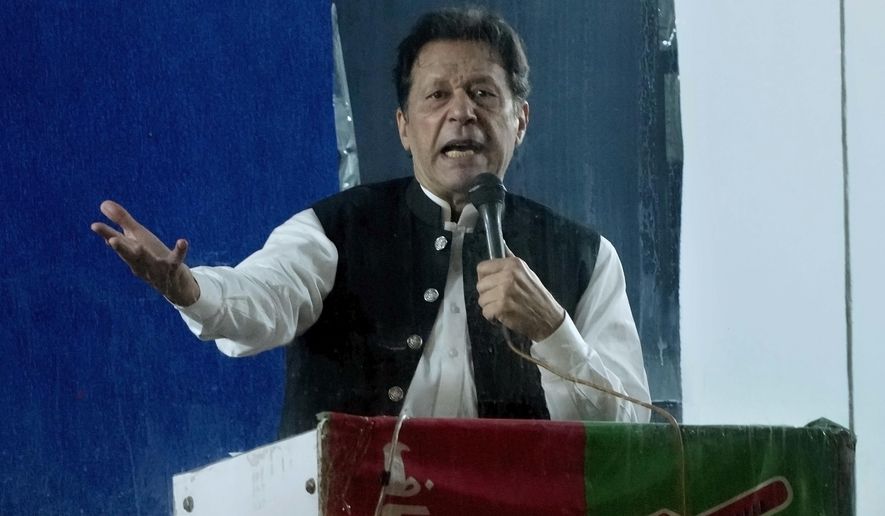 Protected by a bulletproof barrier, former Prime Minister Imran Khan speaks during a rally in Lahore, Pakistan, Sunday, March 26, 2023, to pressure the government of Shahbaz Sharif to agree to hold snap elections. (AP Photo/K.M. Chaudary)