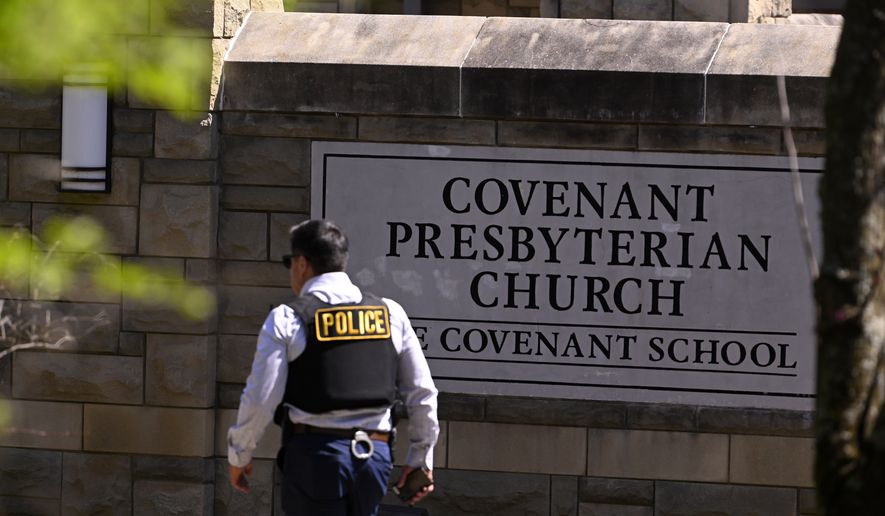 A police officer walks by an entrance to The Covenant School after a shooting in Nashville, Tenn. on Monday, March 27, 2023.  (AP Photo/John Amis)