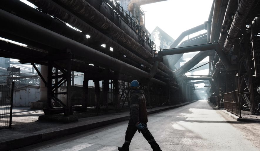 A worker walks inside the Zaporizhstal steel plant, in Zaporizhia, Ukraine, Wednesday, March 1, 2023. The southwestern city of Zaporizhzhia, which gives the plant its name, is less than 50 kilometers (31 miles) from the front line and its residential buildings and energy infrastructure are a frequent Russian target. The impact of the war has left the plant running below full capacity, with a third of its 10,000 workers idle. (AP Photo/Thibault Camus)