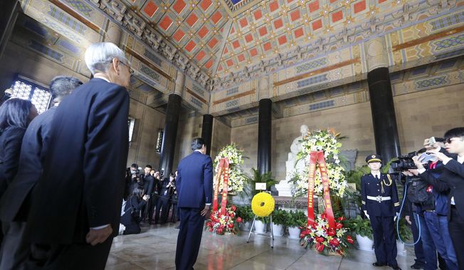 In this photo released by the Ma Ying-jeou Office, former Taiwan President Ma Ying-jeou, center, stands at the Mausoleum of Sun Yat-sen in Nanjing in eastern China&#x27;s Jiangsu Province, Tuesday, March 28, 2023. Ma departed for a tour of China on Monday, in what he called an attempt to reduce tensions a day after Taiwan lost one of its few remaining diplomatic partners to China. (Ma Ying-jeou Office via AP)