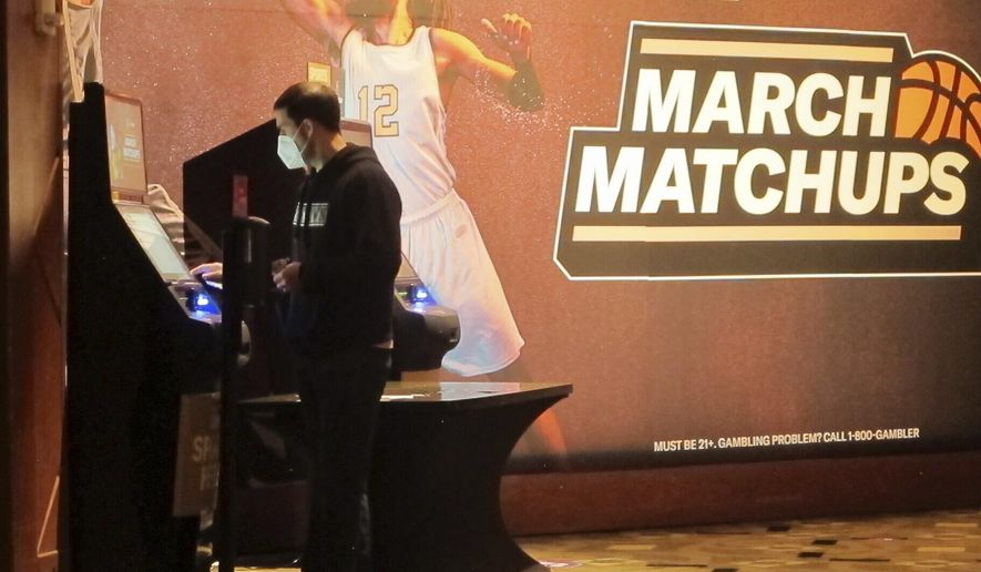 A man makes a bet at a kiosk in the Borgata casino in Atlantic City NJ on March 19, 2021 at the start of the March Madness college basketball tournament. On March 28, 2023, the American Gaming Association issued a new marketing code prohibiting sports books from partnering with colleges to promote sports wagering, banning payments to college and amateur athletes for the use of their name, image or likeness, and ending the use of terms including &quot;free&quot; or &quot;risk-free&quot; to describe promotional bets (AP Photo/Wayne Parry)