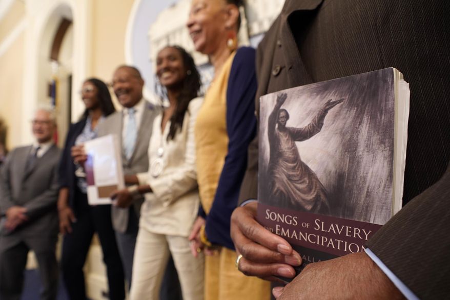 Dr. Amos C. Brown Jr., vice chair for the California Reparations Task Force, right, holds a copy of the book "Songs of Slavery and Emancipation," as he and other members of the task force pose for photos at the Capitol in Sacramento, Calif., on June 16, 2022. Economists for a California reparations task force estimate the state owes Black residents at least $800 billion for harms in policing, housing and health. The preliminary estimate will be discussed at the Wednesday, March 29, 2023, meeting of the state reparations task force. (AP Photo/Rich Pedroncelli) **FILE**