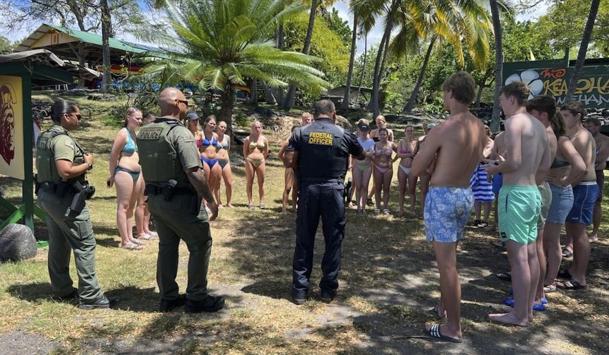 In this photo provided by the Hawaii Department of Land and Natural Resources, department enforcement officers speak to swimmers in Honaunau, Hawaii, March 26, 2023, after the swimmers allegedly harassed a pod of wild spinner dolphins. (Hawaii Department of Land and Natural Resources via AP)