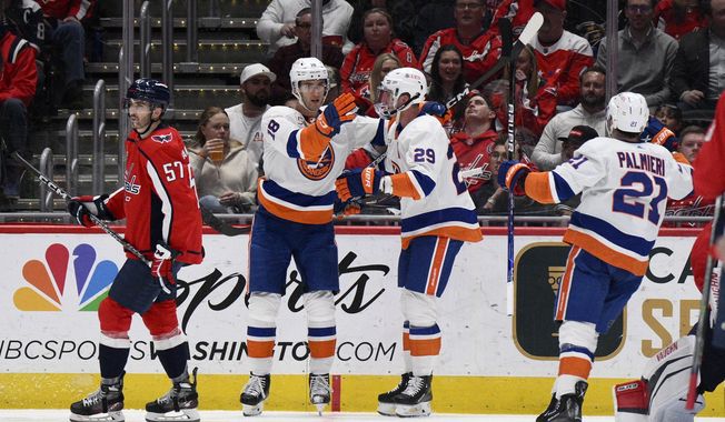 New York Islanders left wing Pierre Engvall (18) celebrates his goal with center Brock Nelson (29) and center Kyle Palmieri (21) during the second period of an NHL hockey game next to Washington Capitals defenseman Trevor van Riemsdyk (57), Wednesday, March 29, 2023, in Washington. (AP Photo/Nick Wass)