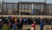 Migrants mill around on the U.S. side of the border next to a gate guarded by U.S. authorities, after crossing from the Mexican side in Ciudad Juarez, Wednesday, March 29, 2023, a day after dozens of migrants died in a fire at a migrant detention center in Ciudad Juarez. (AP Photo/Fernando Llano)