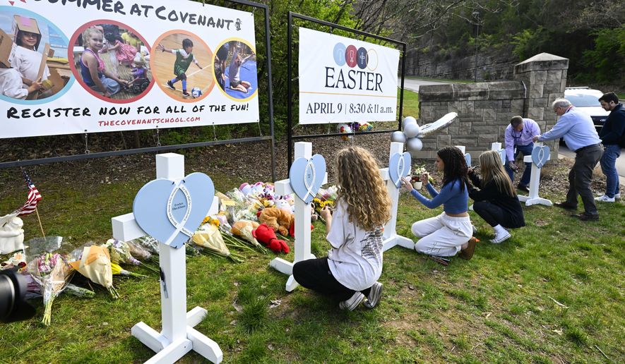 Girls write messages on crosses at an entry to Covenant School, Tuesday, March 28, 2023, in Nashville, Tenn., which has become a memorial for the victims of Monday&#x27;s school shooting. (AP Photo/John Amis)
