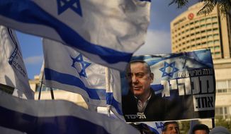 Right-wing Israelis rally in support of Prime Minister Benjamin Netanyahu, seen in poster, and his government&#x27;s plans to overhaul the judicial system, in Tel Aviv, Israel, Thursday, March 30, 2023. (AP Photo/Ariel Schalit)