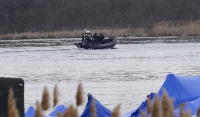 A police boat searches an area in Akwesasne, Quebec, Friday, March 31, 2023. Authorities in the Mohawk Territory of Akwesasne said Friday one child is missing after the bodies of six migrants of Indian and Romanian descent were pulled from a river that straddles the Canada-U.S. border. (Ryan Remiorz/The Canadian Press via AP)