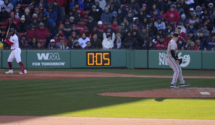 Baltimore Orioles relief pitcher Logan Gillaspie, right, starts to deliver a pitch to Boston Red Sox&#x27;s Connor Wong, as the pitch clock ticks to five seconds, during the eighth inning of an opening day baseball game at Fenway Park, Thursday, March 30, 2023, in Boston. (AP Photo/Charles Krupa)