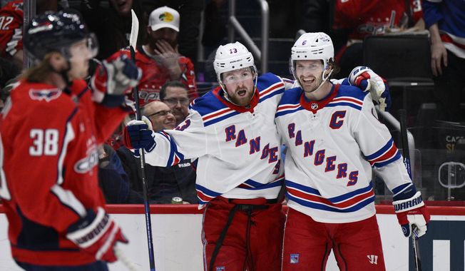 New York Rangers left wing Alexis Lafrenière (13) celebrates his goal with defenseman Jacob Trouba, right, as Washington Capitals defenseman Rasmus Sandin (38) skates by during the first period of an NHL hockey game, Sunday, April 2, 2023, in Washington. (AP Photo/Nick Wass)