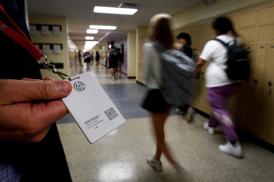 Brent Kiger, Olathe Public Schools' director of safety service, displays a panic-alert button while students at Olathe South High School rush between classes, Aug. 19, 2022, in Olathe, Kan. The district introduced the buttons, which allow staff to trigger a lockdown that will be announced with flashing strobe lights, a takeover of staff computers and a prerecorded intercom announcement, at the start of this school year as part of $2.1 million plan to make district schools more secure. In the wake of a deadly elementary school shooting in Tennessee earlier this week, state lawmakers across the country are moving forward with school safety measures. (AP Photo/Charlie Riedel, File)