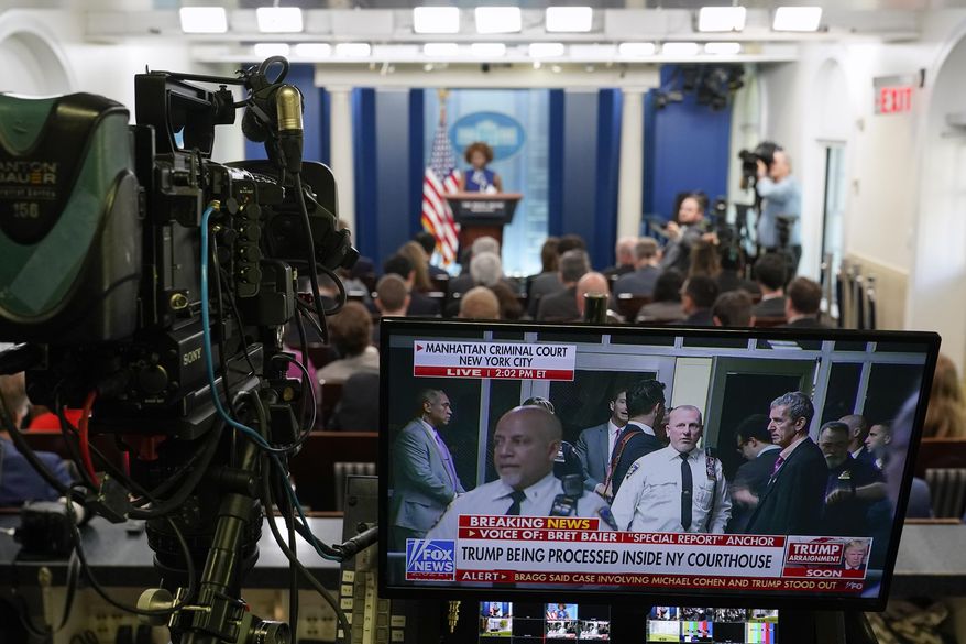 A television broadcasts news of former President Donald Trump's Manhattan courthouse appearance is seen on a video monitor as White House press secretary Karine Jean-Pierre speaks during a press briefing at the White House, Tuesday, April 4, 2023, in Washington. (AP Photo/Patrick Semansky)