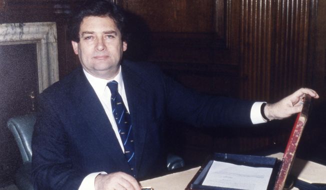 Preparing his budget, Britain&#x27;s Chancellor of the Exchequer, Nigel Lawson, with his famous battered red Budget Box, in his office at the Treasury, London, March 10, 1987. Lawson, the tax-cutting U.K. Treasury chief under the late Margaret Thatcher and a lion of Conservative politics in the late 20th century has died. He was 91. (AP Photo/Gerald Penny, File)