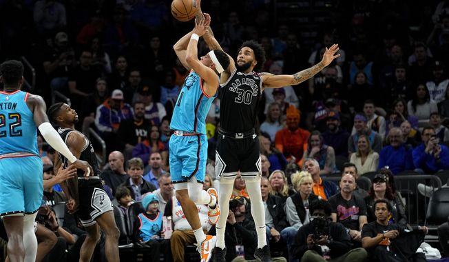 Phoenix Suns guard Devin Booker is fouled by San Antonio Spurs forward Julian Champagnie (30) during the first half of an NBA basketball game, Tuesday, April 4, 2023, in Phoenix. (AP Photo/Matt York)
