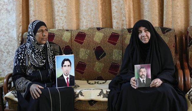 Nidal Ali, right, and Nawal Sweidan hold photos of their missing sons in Mahmoudiya, south of Baghdad, Iraq, Tuesday, March 28, 2023. Their sons were both kidnapped by extremist groups in 2014. Though active conflict in Iraq has largely subsided, many are still waiting to learn the fate of missing loved ones who disappeared during the US invasion, the subsequent civil war, or during the war against the Islamic State. (AP Photo/Hadi Mizban)
