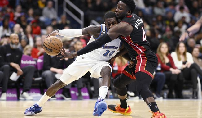 Miami Heat guard Victor Oladipo (4) reaches for the ball against Washington Wizards guard Kendrick Nunn (20) during the first half of an NBA basketball game Friday, April 7, 2023, in Washington. (AP Photo/Nick Wass)