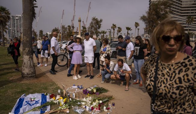 People gather and lay flowers at the site where Alessandro Parini, an Italian tourist, was killed in a Palestinian attack, in Tel Aviv, Israel, Saturday, April 8, 2023. Israeli authorities said an Italian tourist was killed and five other Italian and British citizens were wounded Friday when a car rammed into a group of tourists in Tel Aviv. (AP Photo/Oded Balilty)