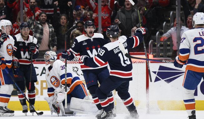 Washington Capitals center Craig Smith (16) celebrates after his goal against New York Islanders goaltender Ilya Sorokin (30) with center Nicklas Backstrom (19) during the first period of an NHL hockey game Monday, April 10, 2023, in Washington. (AP Photo/Nick Wass)