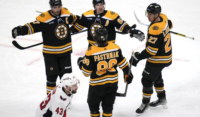 Boston Bruins left wing Brad Marchand, center rear, is congratulated after his goal against the Washington Capitals during the second period of an NHL hockey game Tuesday, April 11, 2023, in Boston. At bottom is Capitals right wing Tom Wilson. (AP Photo/Charles Krupa)