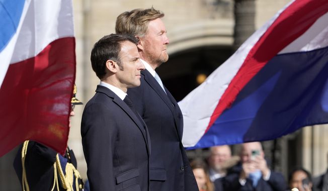 French President Emmanuel Macron, left, and Dutch King Willem-Alexander listen to national anthems outside the royal palace on Dam square in Amsterdam, Netherlands, Tuesday, April 11, 2023. French President Emmanuel Macron begins a two-day state visit to the Netherlands on Tuesday and is making a speech on his vision for the future of Europe. (AP Photo/Peter Dejong)