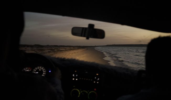 A beach is illuminated by a car&#x27;s headlights at dusk near Nouadhibou, Mauritania, Thursday, Nov. 25, 2021. (AP Photo/Felipe Dana)