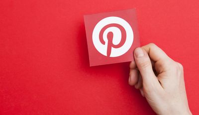A hand holds a Pinterest logo on May 7, 2017, in London. (File photo credit: Ink Drop via Shutterstock)