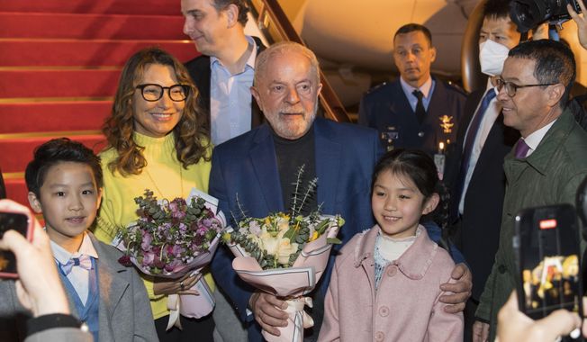 In this photo released by Xinhua News Agency, Brazilian President Luiz Inacio Lula da Silva, center, and first lady Rosangela Silva, second left, receive flowers presented by children from the Shanghai Children&#x27;s Palace of the China Welfare Institute upon arrival in Shanghai, China on Wednesday, April 12, 2023. Lula was in the Chinese financial hub of Shanghai on Thursday in a bid to boost ties with the South American giant&#x27;s biggest trade partner and win political support for attempts to mediate the conflict in Ukraine. (Gao Feng/Xinhua via AP)