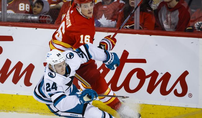 San Jose Sharks forward Jacob Peterson (24) is checked by Calgary Flames defenseman Nikita Zadorov during the first period of an NHL hockey game Wednesday, April 12, 2023, in Calgary, Alberta. (Jeff McIntosh/The Canadian Press via AP)