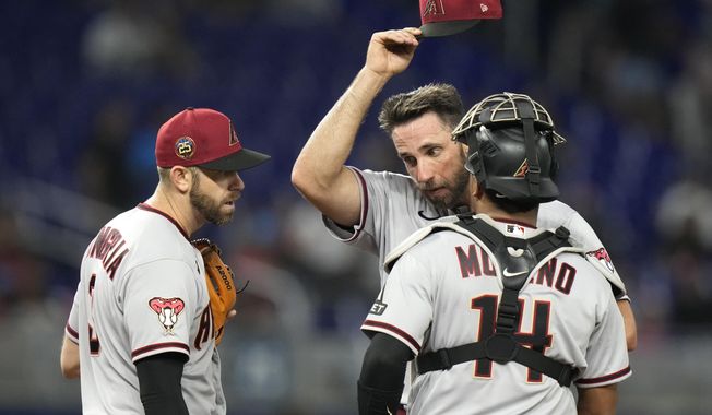 Arizona Diamondbacks starting pitcher Madison Bumgarner, center, stands on the mound with third baseman Evan Longoria, left, and catcher Gabriel Moreno (14) during the fourth inning of a baseball game against the Miami Marlins, Friday, April 14, 2023, in Miami. (AP Photo/Lynne Sladky)