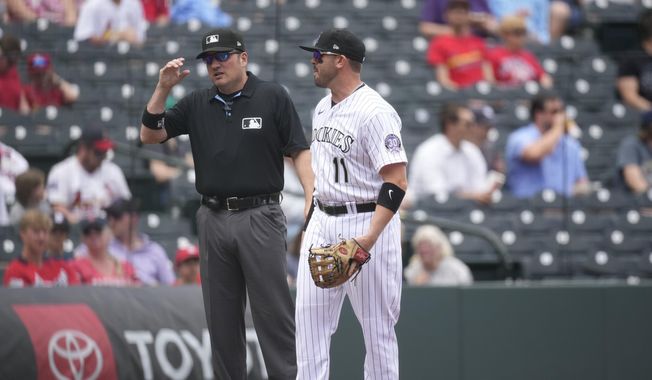 Third base umpire Dan Bellino, left talks briefly with Colorado Rockies third baseman Mike Moustakas as players take the field for a baseball game against the St. Louis Cardinals, Wednesday, April 12, 2023, in Denver. Small talk has become an artifact from a past time in Major League Baseball as the pitch clock — and the penalties that can be handed out for violating the new rules that have come with it — has reduced socialization on the diamond. (AP Photo/David Zalubowski)