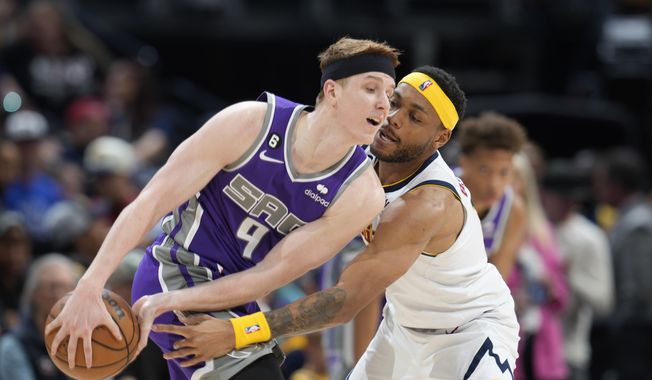 Sacramento Kings guard Kevin Huerter, left, protects the ball as Denver Nuggets forward Bruce Brown defends in the second half of an NBA basketball game, Sunday, April 9, 2023, in Denver. (AP Photo/David Zalubowski)