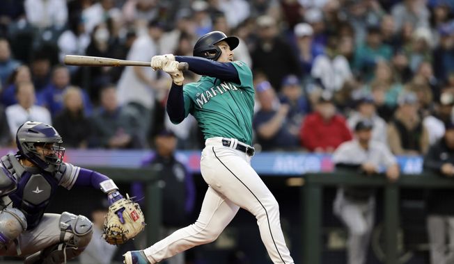 Seattle Mariners left fielder Jarred Kelenic, right, hits a home run, also scoring Teoscar Hernandez, off a pitch from Colorado Rockies starter Austin Gomber during the second inning of a baseball game, Friday, April 14, 2023, in Seattle. (AP Photo/John Froschauer)